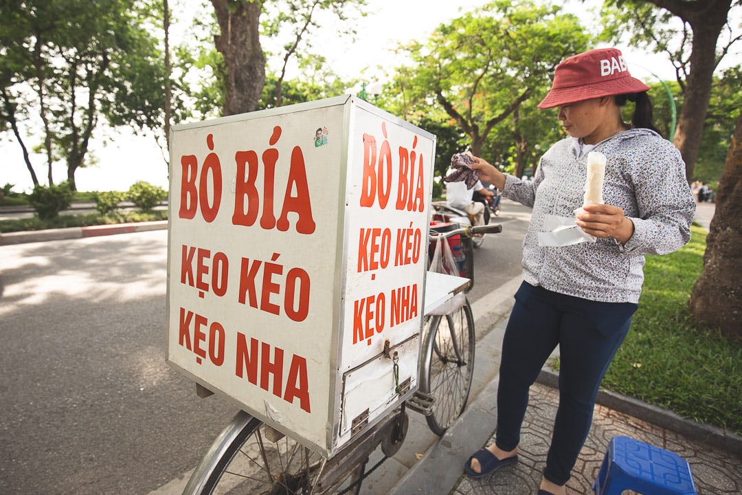 A woman on a bike sells bo bia ngot a dessert commonly found in Hanoi, Vietnam