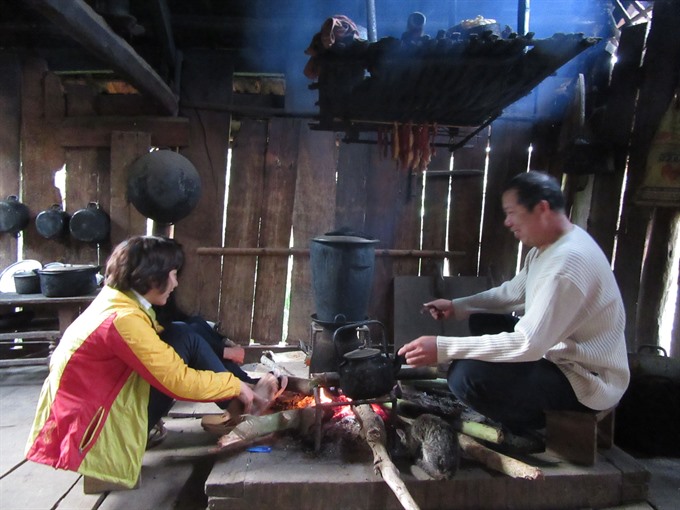 Creative chef: Lò Văn Thỏa explains about local culture around the kitchen in his stilt house, under hanging skewers of smoked buffalo meat. — VNS Photo Bạch Liên